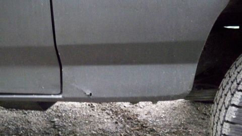 1994 Ford Bronco - Close-up of a vehicle's lower body panel and tire, showing a small rust spot.
