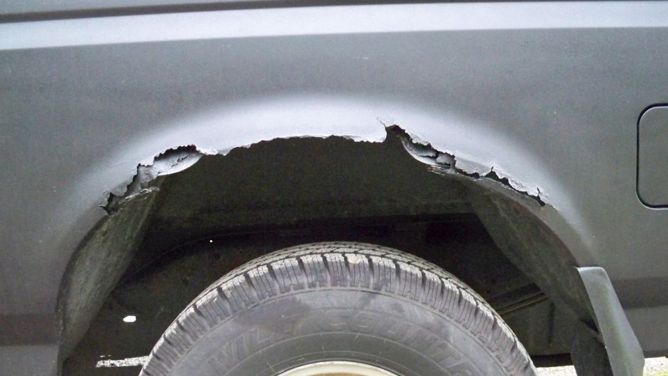Rusted rear wheel well on a dark vehicle