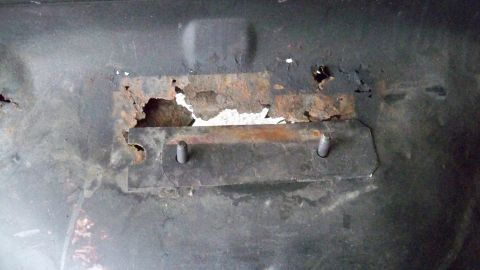 1994 Ford Bronco - Corroded metal bracket with bolts, likely from a vehicle's undercarriage or frame.