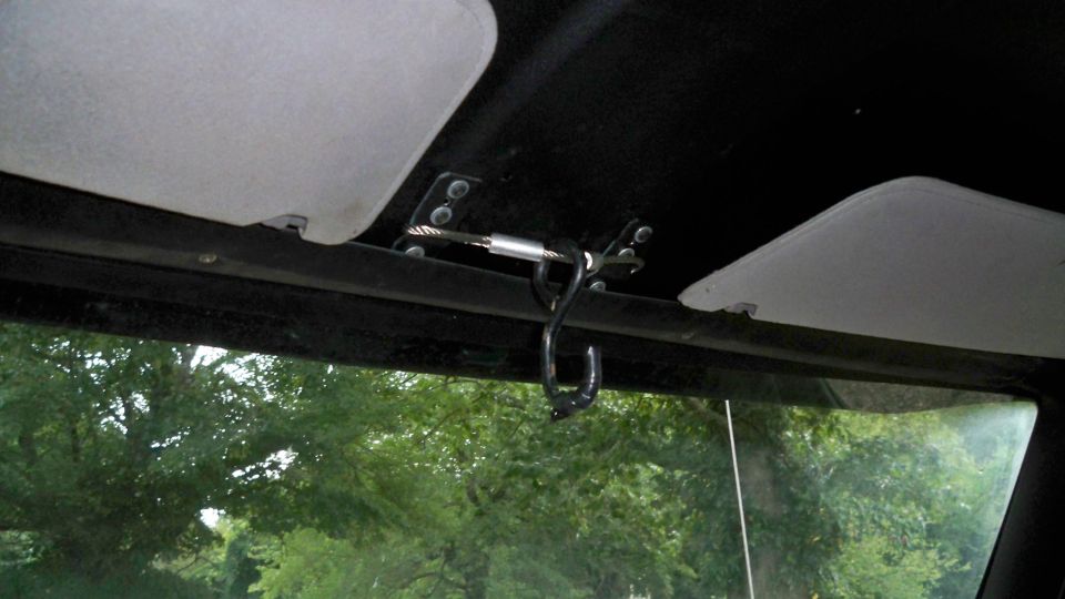 Interior view of a vehicle's headliner with two sun visors and a black hook attached to a metal rod