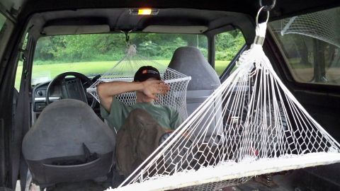 1994 Ford Bronco - A person relaxes in a hammock strung up inside the cabin of a vehicle.