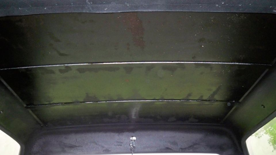 Black interior ceiling with horizontal panel lines and a latch. Water stains visible