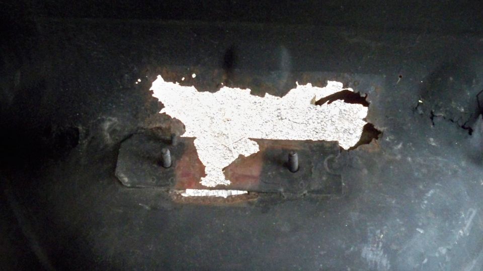 Rust hole in vehicle undercarriage with visible mounting points