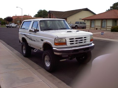 1996 Ford Bronco - A lifted 1996 Ford Bronco is parked on the street in front of a house, with another truck visible in the background.