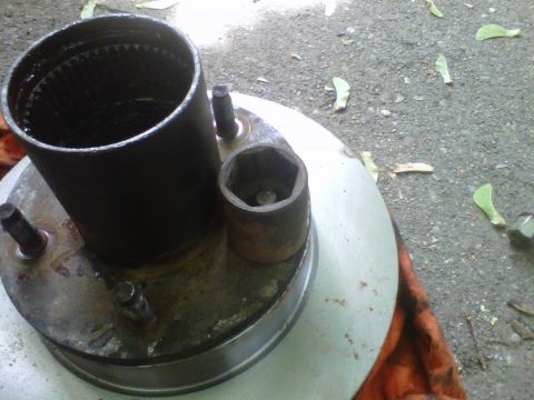 1995 Ford Bronco - Close-up of a hub and brake rotor assembly resting on an orange shop rag on gravel, with the internally splined hub barrel standing up in t…