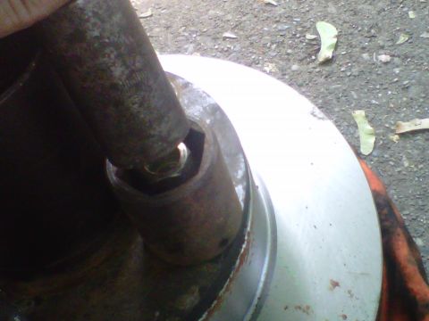 1995 Ford Bronco - A rusty deep socket is stacked over a wheel stud on a hub as an improvised press, with a second socket or drive extension seated on top of…