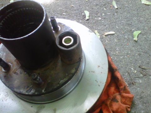 1995 Ford Bronco - A rusty socket sits upright over one wheel stud on a hub, with a lug nut visible down inside the socket bore. The hub is bolted to a machin…