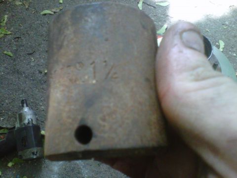 1995 Ford Bronco - A hand holds a heavily rusted impact socket stamped "1 1/4" close to the camera, with a retaining-pin hole visible in its side. An air impa…