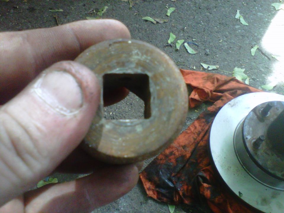 Hand holding a rusty socket showing its square drive, hub and rotor on a rag behind