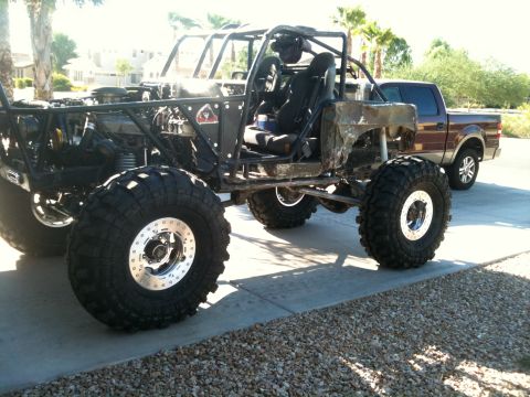 1966 Ford Bronco - This heavily modified off-road buggy features a custom roll cage and oversized tires, with a pickup truck visible in the background.