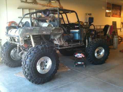 1966 Ford Bronco - Custom buggy with oversized tires and exposed frame is undergoing modifications in a garage.