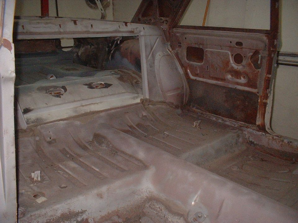 Interior of a 1964 Ford Fairlane showing rusty floor pans and door panels