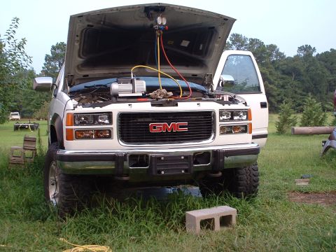 1994 GMC Suburban - A GMC truck is parked outside with its hood open, undergoing air conditioning service.