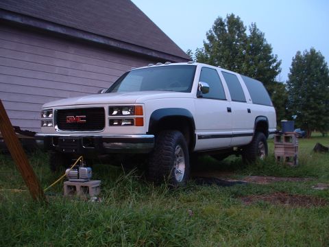 1994 GMC Suburban - A white GMC Suburban is parked in front of a building with a vacuum pump nearby.