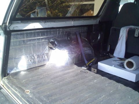 1994 Ford Bronco - The cargo area of a vehicle shows sound deadening material applied to the rear wall and a roll of material on the floor.