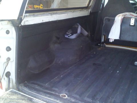 1994 Ford Bronco - Interior view of the cargo area of a 1994 Ford Bronco, showing the black liner and a seatbelt.
