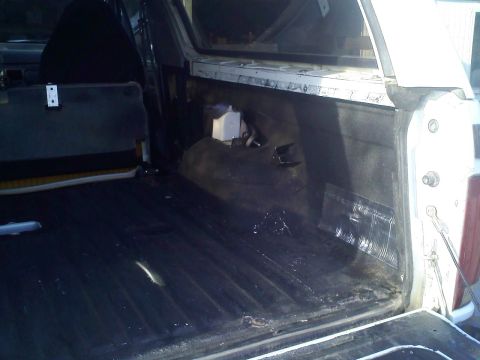 1994 Ford Bronco - The interior cargo area of an SUV shows signs of wear and tear, with some debris present.