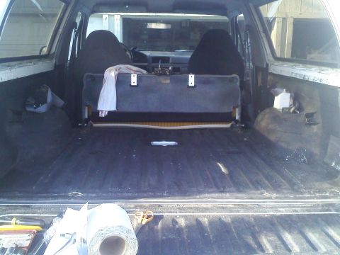 1994 Ford Bronco - The cargo area of a 1990s SUV, with a roll of material and scissors visible on the tailgate.