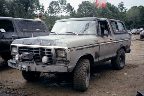 1979 Ford Bronco II - A weathered Ford Bronco sits in a muddy outdoor area, with another vehicle partially visible behind it.