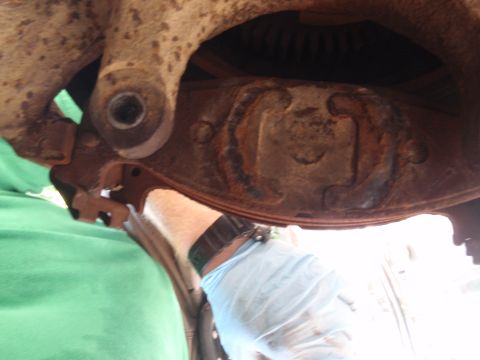 1994 Ford Bronco - Mechanic's gloved hand works on a rusty suspension part, Supermotors.net logo in corner.