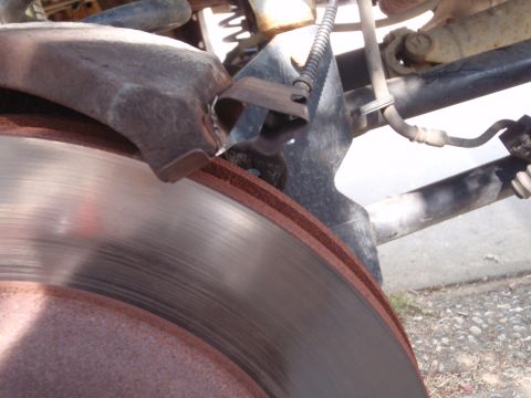 1994 Ford Bronco - Detail of a vehicle's braking system, showing a worn brake rotor and associated suspension components.