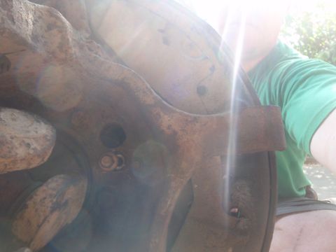 1994 Ford Bronco - Close-up of a heavily rusted brake rotor and caliper bracket assembly.