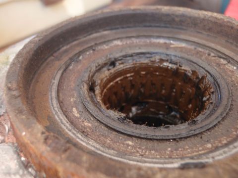 1994 Ford Bronco - This is a close-up view of a heavily corroded and worn ball joint housing, showing signs of significant wear and grease accumulation.