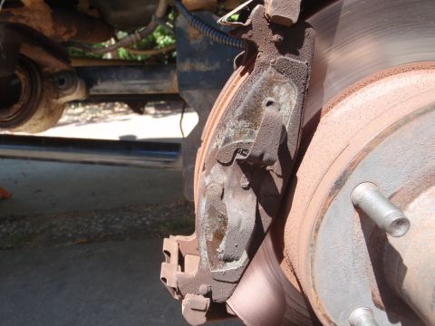1994 Ford Bronco - Close-up of a worn brake caliper and rotor assembly, likely needing replacement.