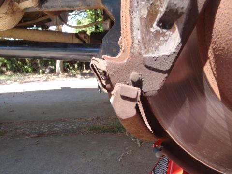 1994 Ford Bronco - Close-up of a vehicle's brake system, showing wear and rust on the caliper and rotor.
