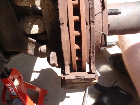 1994 Ford Bronco - This image shows a close-up view of a vehicle's brake system, including a rusty rotor and caliper. A red jack stand is visible to the left.