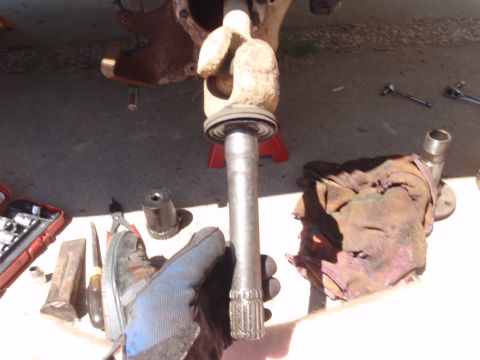 1994 Ford Bronco - Close-up of a splined axle shaft being removed, with tools and a rag visible in the background.