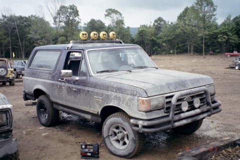 1979 Ford Bronco II - A dirty Ford Bronco is parked in a muddy lot with other vehicles visible in the background.