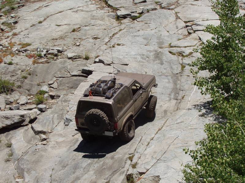 Lifted Ford Bronco SUV climbing a granite rock slab off-road, overhead rear view