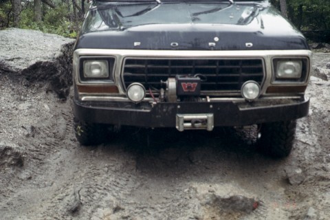 1979 Ford Bronco II - The front of a black 1979 Ford Bronco II is shown navigating a rocky, muddy path.
