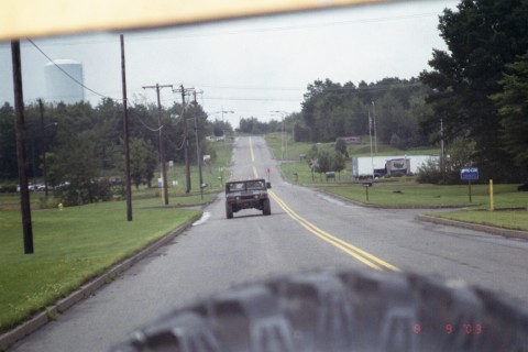 1979 Ford Bronco II - A Humvee travels down a long, straight road, disappearing into the distance under an overcast sky.