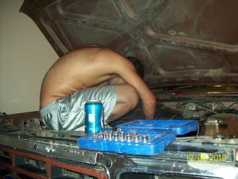 1985 Ford Bronco - A person works on the engine of a vehicle, with a socket set and a beverage can nearby.