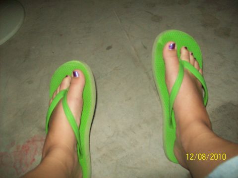 1985 Ford Bronco - A close-up view of feet wearing bright green flip-flops, with purple nail polish visible on the toes.