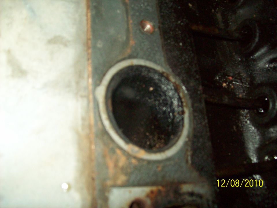 Close-up of an engine cylinder head port with carbon buildup. Watermark shows 12/08/2010 and Supermotors.net