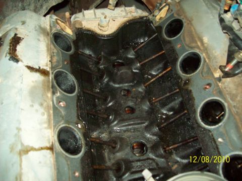 1985 Ford Bronco - Close-up of a heavily soiled engine intake manifold, showing internal components and oil residue.