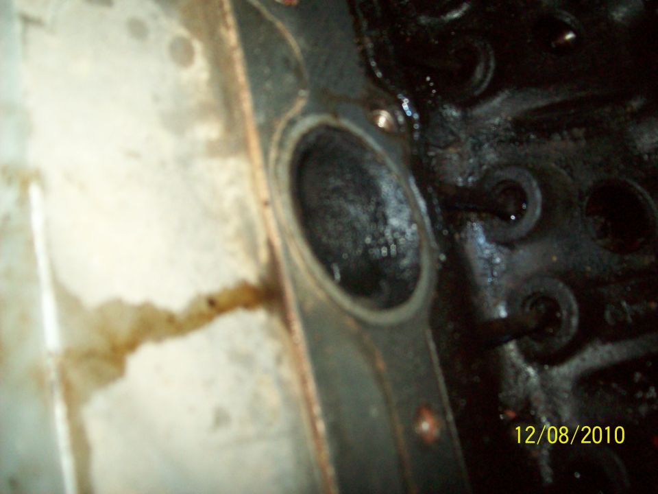 Close-up of an engine's cylinder head gasket area with oil residue
