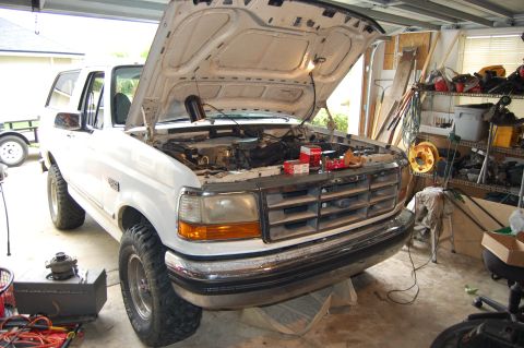 1994 Ford Bronco - A white Ford Bronco is parked in a garage with its hood open, revealing the engine compartment.