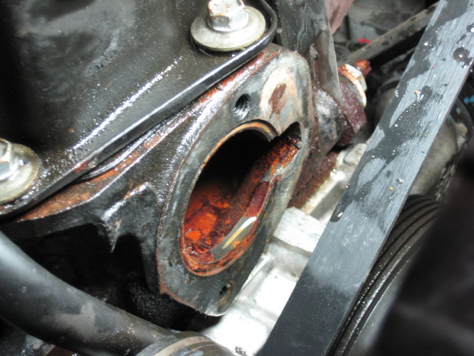 close-up of corroded engine thermostat housing with gasket removed