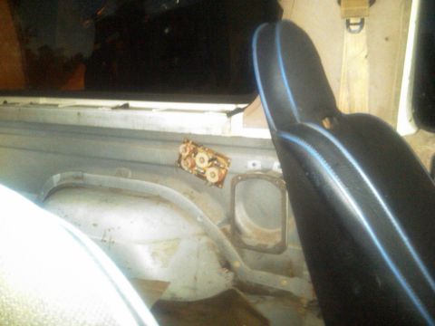 1986 Ford Bronco - Interior view of a vehicle's rear section, revealing exposed metal and a seat with blue piping.