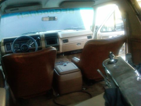 1986 Ford Bronco - The interior of a vehicle shows brown bucket seats and a tan dashboard with a steering wheel.