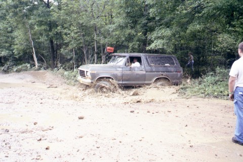 1979 Ford Bronco II - This dark SUV, likely a 1978 Ford Bronco, is deeply stuck in the mud off-road.