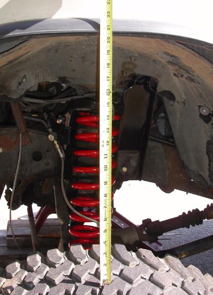 1990 Ford Bronco II - Measuring suspension height with a tape measure next to a red coil spring and tire.
