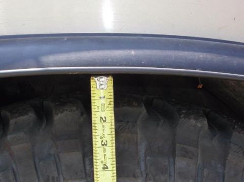 1990 Ford Bronco II - Measuring the gap between the tire and the fender well using a tape measure.