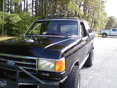 1990 Ford Bronco - This black 1990 Ford Bronco features a roof-mounted light bar and aggressive off-road tires.
