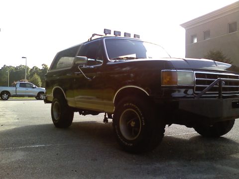 1990 Ford Bronco - 1990 Ford Bronco, modified with a light bar and heavy-duty bumper, seen alongside a pickup truck.