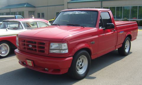 2007 Ford Mustang - A red 1992 Ford F-150 pickup truck is parked next to a classic car.